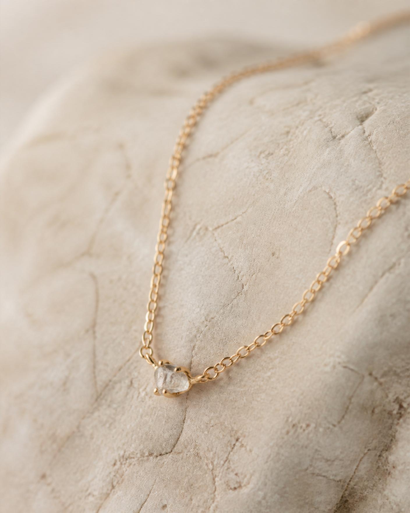 Collar de oro con pequeño diamante en bruto sobre piedra caliza